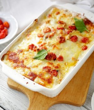 baked lasagna in white dish with tomatoes